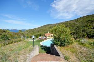 a swimming pool in a field with a house at Villa Redinoce in Marciana