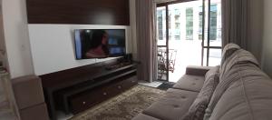 een woonkamer met een bank en een flatscreen-tv bij Amplo apartamento para aluguel diário numa das melhores praias de SC. in Meia Praia