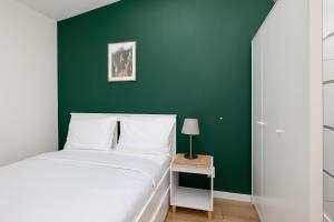 a bedroom with a green accent wall and a bed at Plac Grunwaldzki Happy Apartment in Szczecin