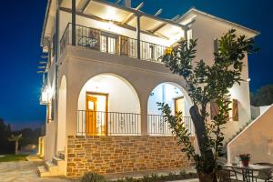 a large white house with a balcony at night at Kostis Orange Resort in Volos