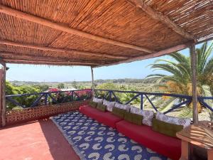 un patio con un sofá rojo bajo un techo de madera en KHAMBEACH, en Azemmour 8 fotos más