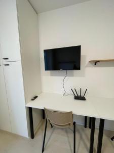 a white desk with a tv on a wall at Garden apartment Brno center in Brno