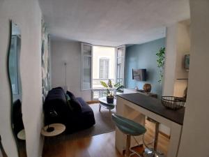ein Wohnzimmer mit einem schwarzen Sofa und einem Schreibtisch in der Unterkunft Studio cosy au cœur de Nîmes. in Nîmes