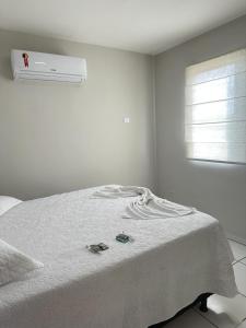 a white bedroom with a bed with a heater on it at Apartamento em Várzea Grande MT in Várzea Grande