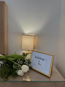 a sign on a table with flowers and a lamp at Lana apartmani in Bar