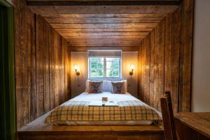 1 dormitorio con 1 cama en una pared de madera en Bourne Valley Inn, en Saint Mary Bourne