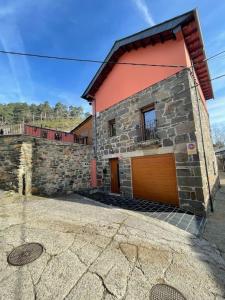 - un bâtiment en briques avec un garage doté d'une porte marron dans l'établissement Villaduranchi, à Villablino