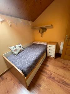 um pequeno quarto com uma cama e piso em madeira em Villaduranchi em Villablino