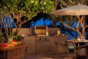 an outdoor kitchen with a table and an umbrella at Ritz Carlton Luxurious Residence on Singer Island in Riviera Beach
