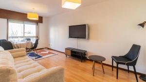 a living room with a couch and a tv on a wall at Charmy Engenheiro António Costa Reis Apartment in Senhora da Hora