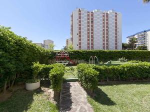 a garden with bushes and a building in the background at Olimpia playa gandia in Playa de Gandia