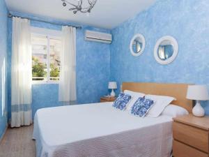 Un dormitorio azul con una cama grande y una ventana en Apartamento jardines playa gandia, en Puerto de Gandía