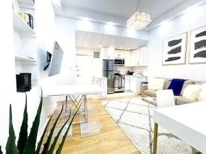 62-2B Renovated 1BR in Prime Upper East Side في نيويورك: غرفة معيشة بيضاء مع أريكة وطاولة