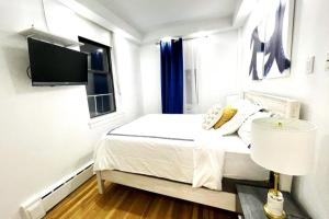 a white bedroom with a bed and a tv at 62-2B Renovated 1BR in Prime Upper East Side in New York