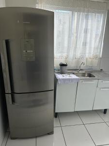 a kitchen with a stainless steel refrigerator and a sink at Apartamento em Várzea Grande MT in Várzea Grande