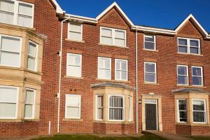 a red brick building with white windows and a door at Ashore@Jubilee in Filey