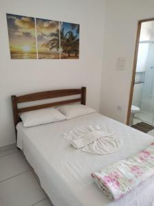 a white bed with two towels on top of it at Pousada Peruíbe Frente ao Mar - Suítes, Kitnets e Apto in Peruíbe