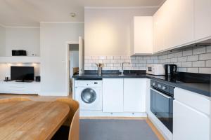 a kitchen with white appliances and a wooden table at Speacial Offer! Bright & Central Apt - Up to 4 in London