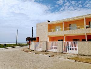 um edifício laranja com uma cerca branca ao lado de uma rua em Pousada Peruíbe Frente ao Mar - Suítes Gourmet em Peruíbe