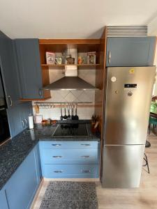 uma cozinha com um frigorífico de aço inoxidável e armários azuis em Villaduranchi em Villablino