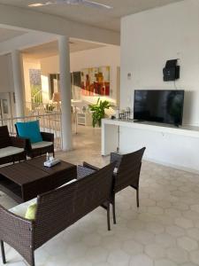 sala de estar con sillas y TV en la pared en Villa Covadonga en Acapulco