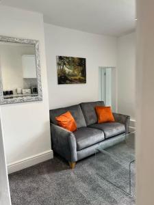 Town Centre Studio Flat في ميرثير تيدفيل: غرفة معيشة مع أريكة رمادية مع وسائد برتقالية