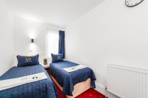 1 dormitorio con 2 camas y reloj en la pared en Jubilee Hotel Victoria, en Londres