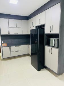 a kitchen with white cabinets and a black refrigerator at Linda casa em condomínio in Tatuí