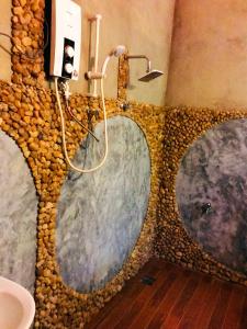 a bathroom with a stone wall with three shower heads at Atha Safari Resort & Riverside Camping in Udawalawe