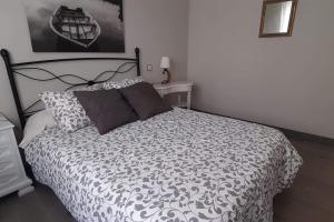 1 dormitorio con 1 cama con edredón blanco y negro en A pocos pasos del faro de Llanes, en Llanes