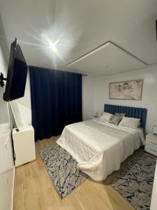 1 dormitorio con 1 cama grande y cortina azul en Coralia Bel F3 clim wifi parking privé Iptv en Oujda