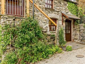 a stone building with a wooden door and a bush at 1 Bed in Crosthwaite LCC70 in Crosthwaite