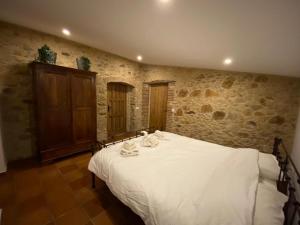 1 dormitorio con 1 cama blanca en una pared de piedra en Can Massanet, en Llagostera