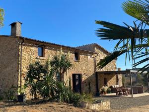 una casa de piedra con palmeras delante en Can Massanet, en Llagostera