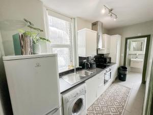 a kitchen with a sink and a washing machine at Lovely 2 bedroom flat in Shepherd's Bush with indoor fire place in London