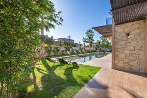 ein paar Bänke auf dem Gras neben einem Pool in der Unterkunft Palais Rafi in Marrakesch