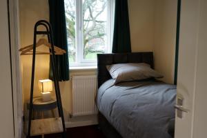 1 dormitorio con cama y ventana en SwiftStayUK - 3-Bed fully furnished house near Wolverhampton, Walsall, Cannock - Contractors & Professional workers & Leisure en Pelsall