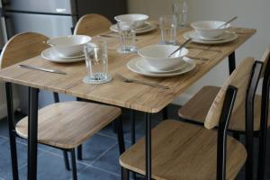 una mesa de madera con sillas, cuencos y vasos. en SwiftStayUK - 3-Bed fully furnished house near Wolverhampton, Walsall, Cannock - Contractors & Professional workers & Leisure, en Pelsall