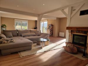 ein Wohnzimmer mit einem Sofa und einem Kamin in der Unterkunft La Ribambelle maison 10 personnes au calme in Tendon