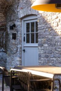 eine weiße Tür mit einem Fenster auf einem Steingebäude in der Unterkunft The Cottage, Everards Farm in Chewton Mendip