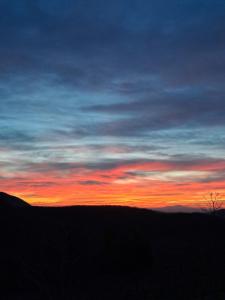 Un tramonto nel cielo su una collina di Agriturismo Le Case ad Assisi