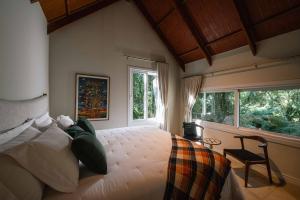 a bedroom with a bed and a chair and windows at Vila Manaca Da Serra in Canela