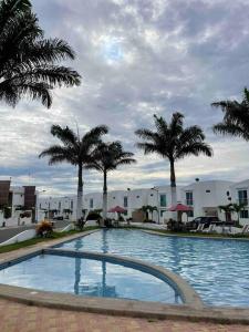 a large swimming pool with palm trees and buildings at Casa con piscina súper bonita ! in Salinas