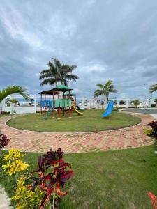 a park with a playground with a slide and palm trees at Casa con piscina súper bonita ! in Salinas