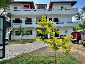 a white building with a tree in front of it at Unic Residence And Transit Hotel in Katunayake