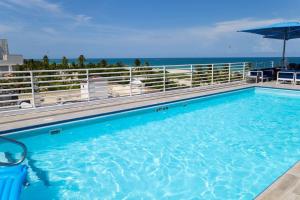 a large swimming pool with the ocean in the background at 1-Bed Apt with rooftop pool Ocean Dr by the Beach in Miami Beach