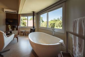 a bathroom with a tub and a large window at Vila Manaca Da Serra in Canela