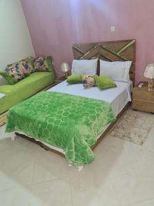una camera da letto con un grande letto e un piumone verde di Auberge Mandar itto A station de service ZIZ a Aït nʼTaleb Akka