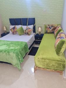 1 Schlafzimmer mit 2 Betten mit grüner Bettwäsche und einem Stuhl in der Unterkunft Auberge Mandar itto A station de service ZIZ in Aït nʼTaleb Akka
