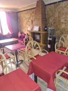 una sala con tavoli, sedie e un camino di Auberge Mandar itto A station de service ZIZ a Aït nʼTaleb Akka